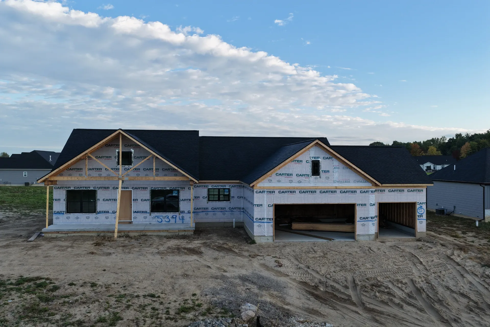 Craftsman-style spec home with white sheathing and black shingle roof
