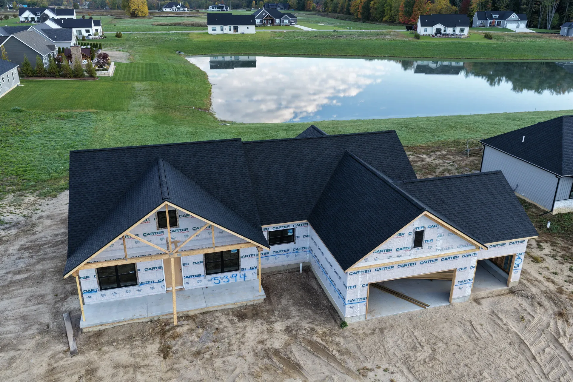 Aerial view of a spec home under construction beside the pond