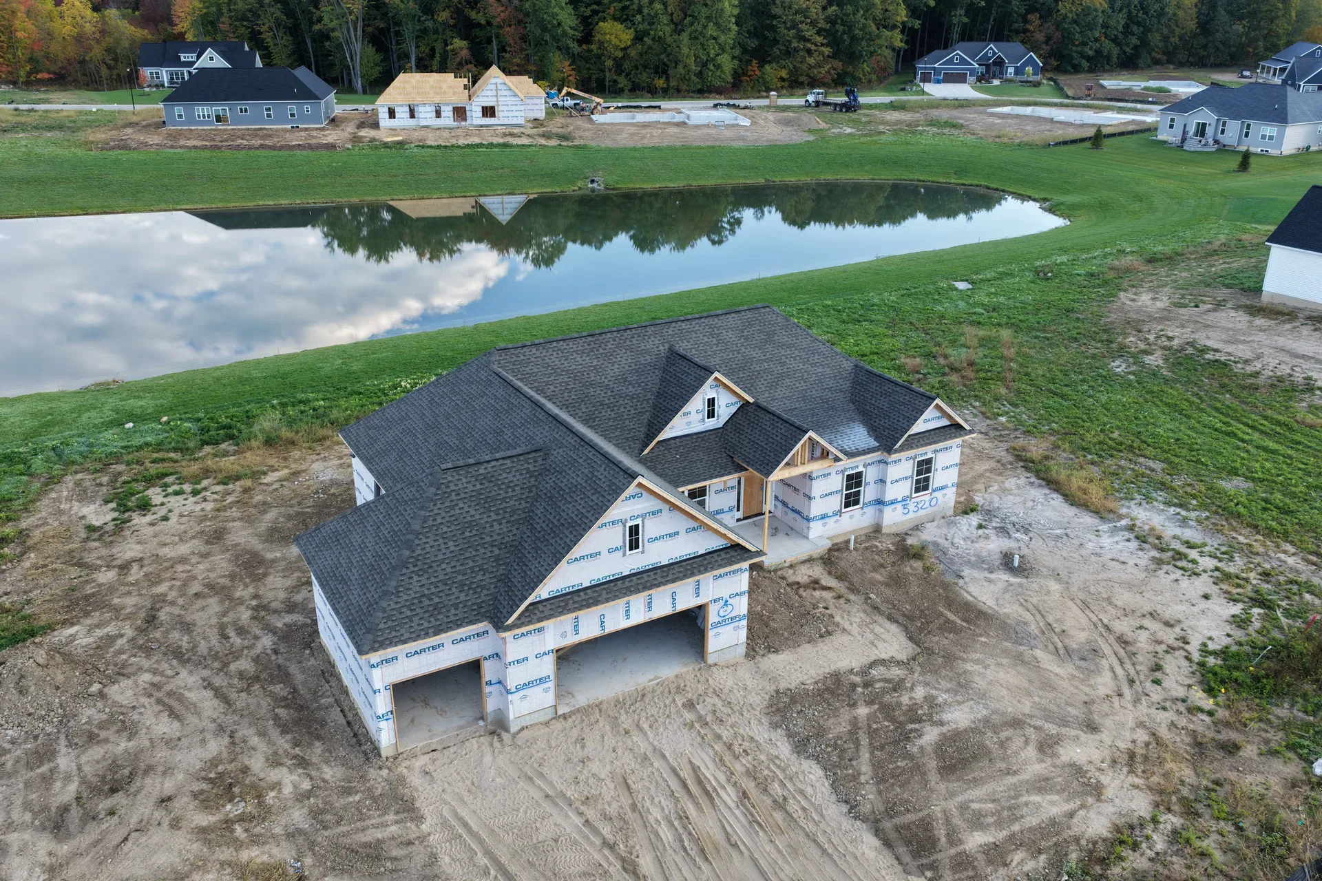 Aerial view of a ranch-style spec home wrapped in weather barrier