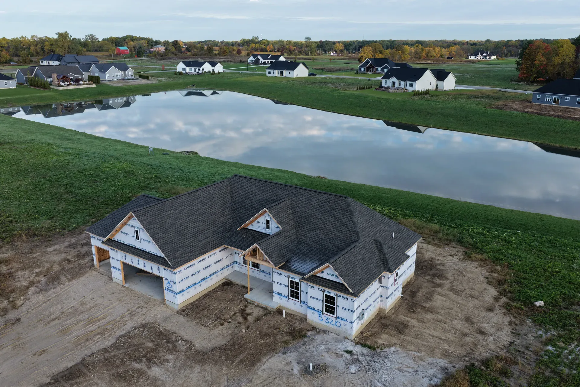 Aerial view of a spec home at golden hour near the pond