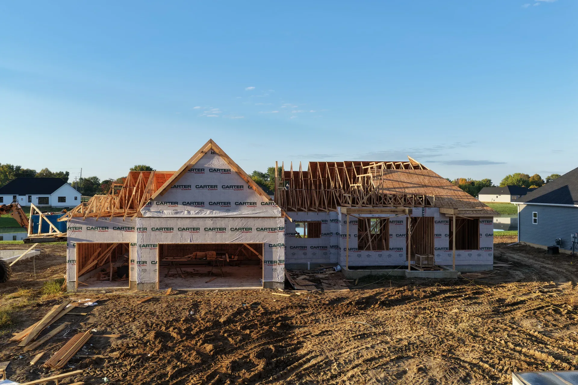 Traditional-style spec home framing under a clear blue sky