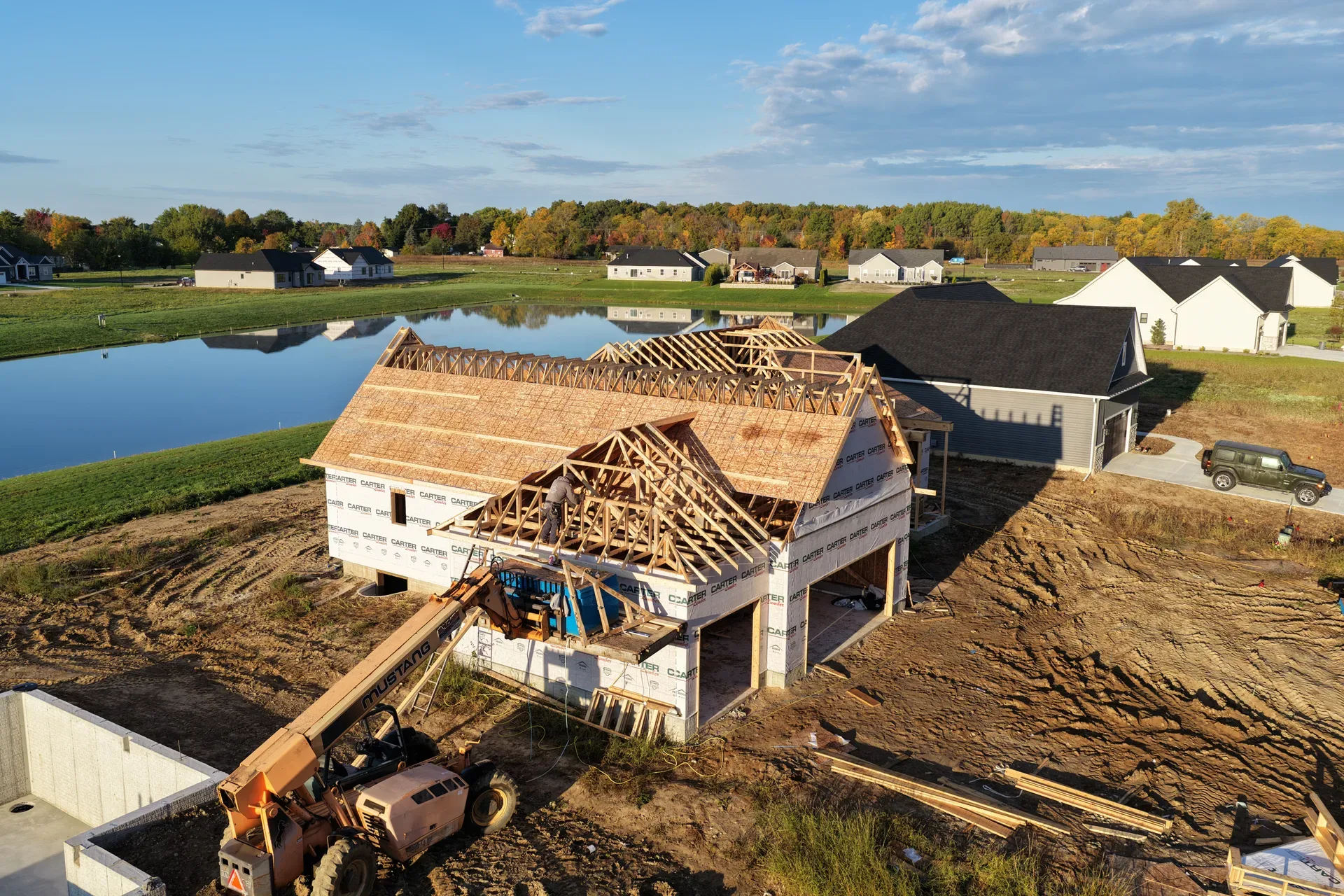 Aerial view of a framed spec home with the pond beyond