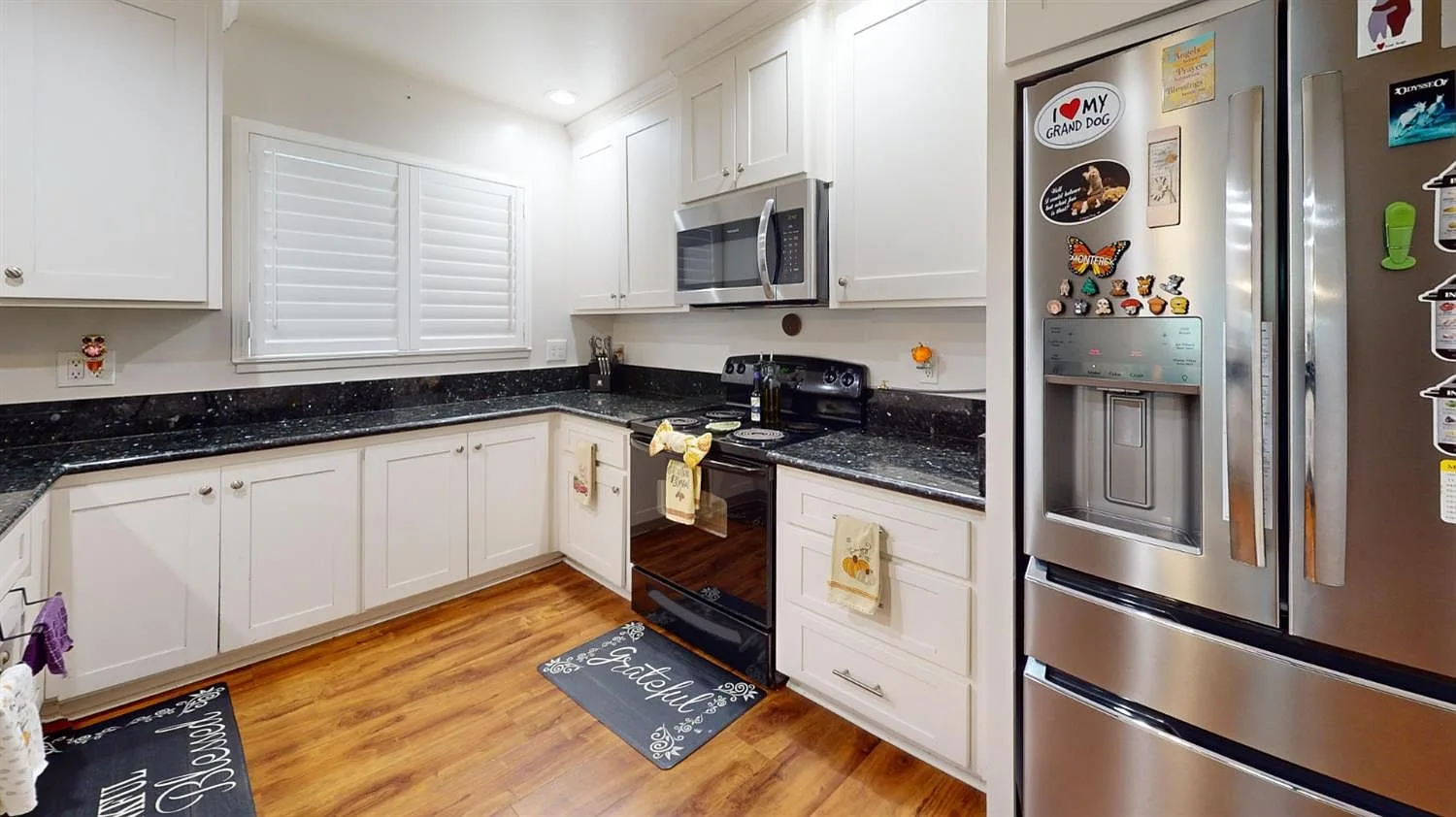 Kitchen with white shaker cabinetry, dark countertops, and stainless steel appliances