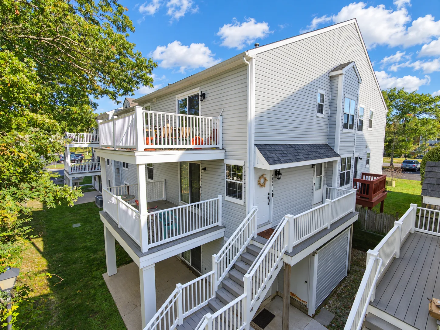 Exterior view of 4885 Bayberry Place, a grey-sided end-unit condominium with elevated deck in Mays Landing NJ