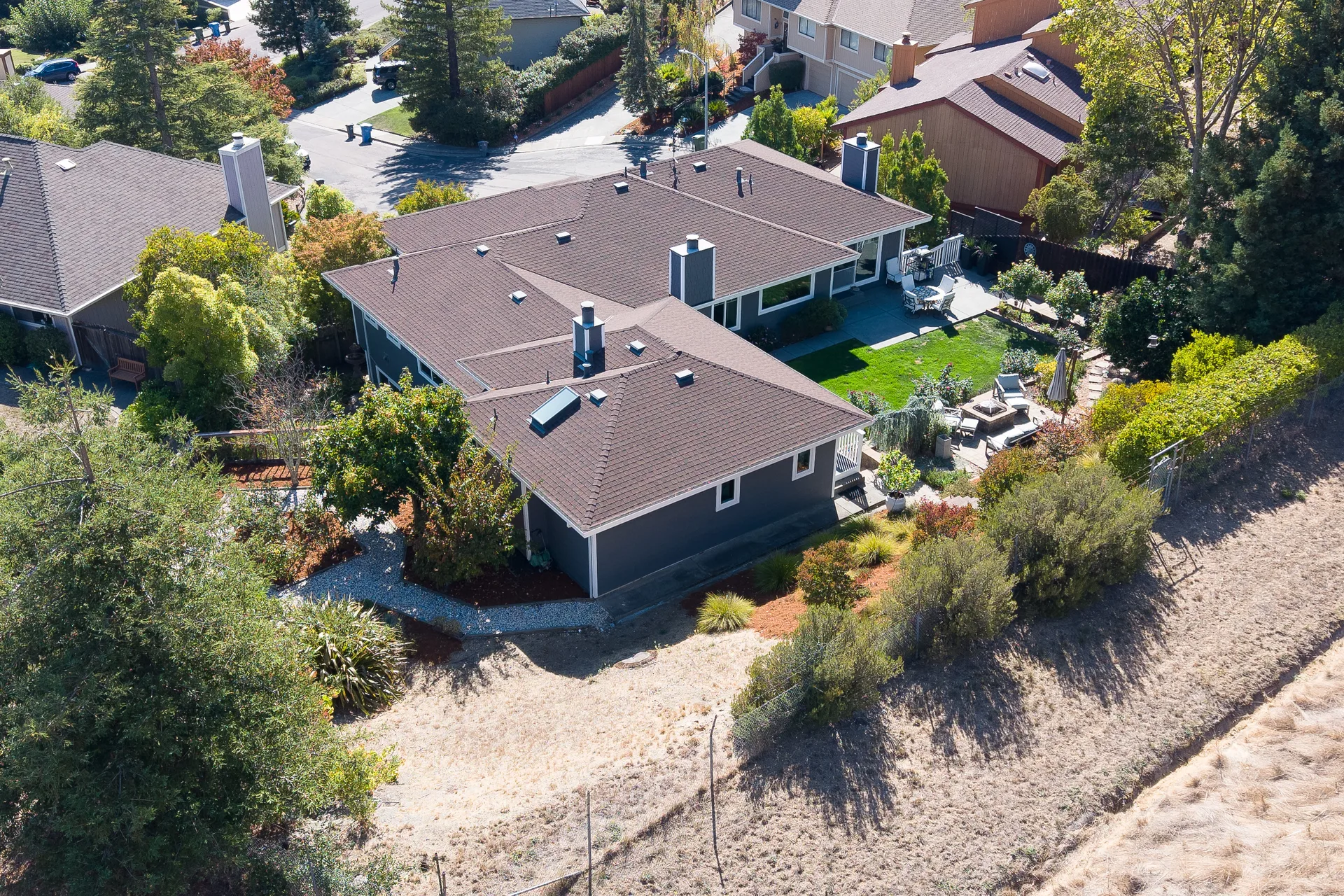 Aerial view of the property's rear yard, patio and terraced gardens leading to open space