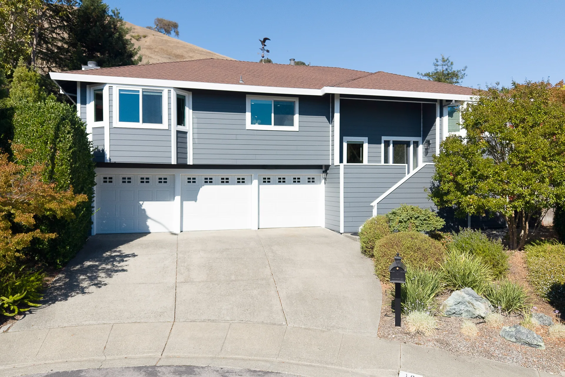 Front exterior of 10 Santa Yorma Ct, a blue-gray Hardie-sided home with white trim and a three-car garage on a Novato cul-de-sac