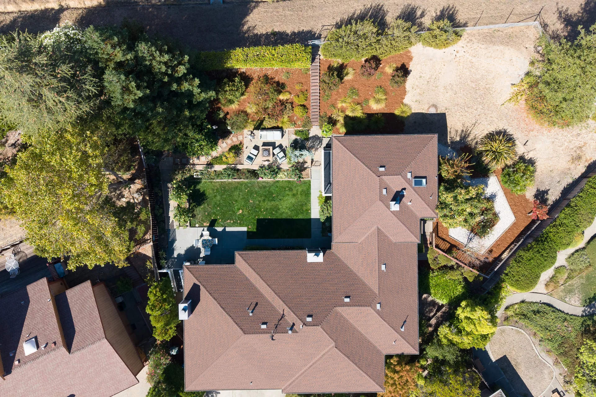 Straight-down drone view of the stamped concrete patio, fire pit area and terraced gardens