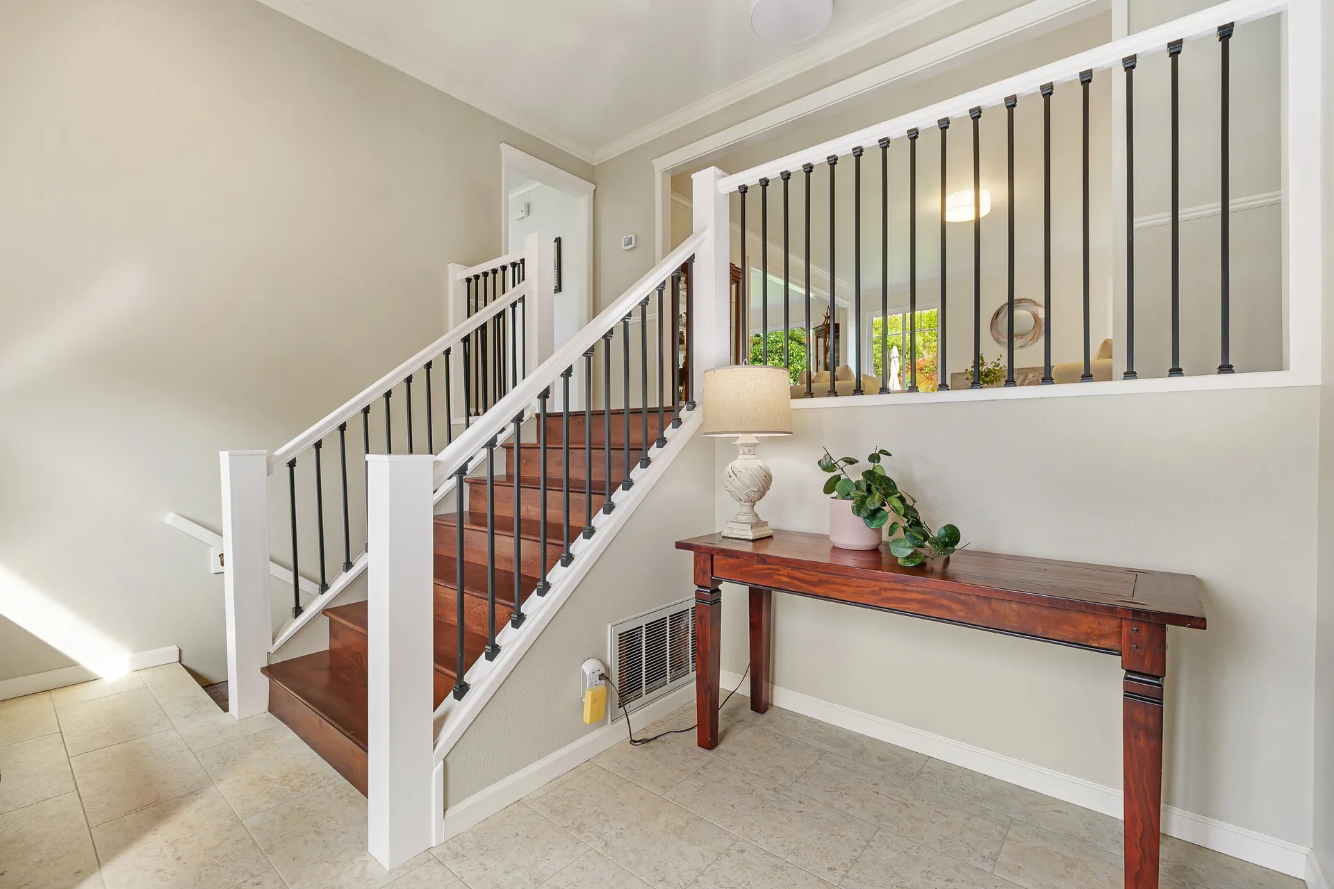 Entryway with white trim, dark stair treads, black balusters and tile flooring