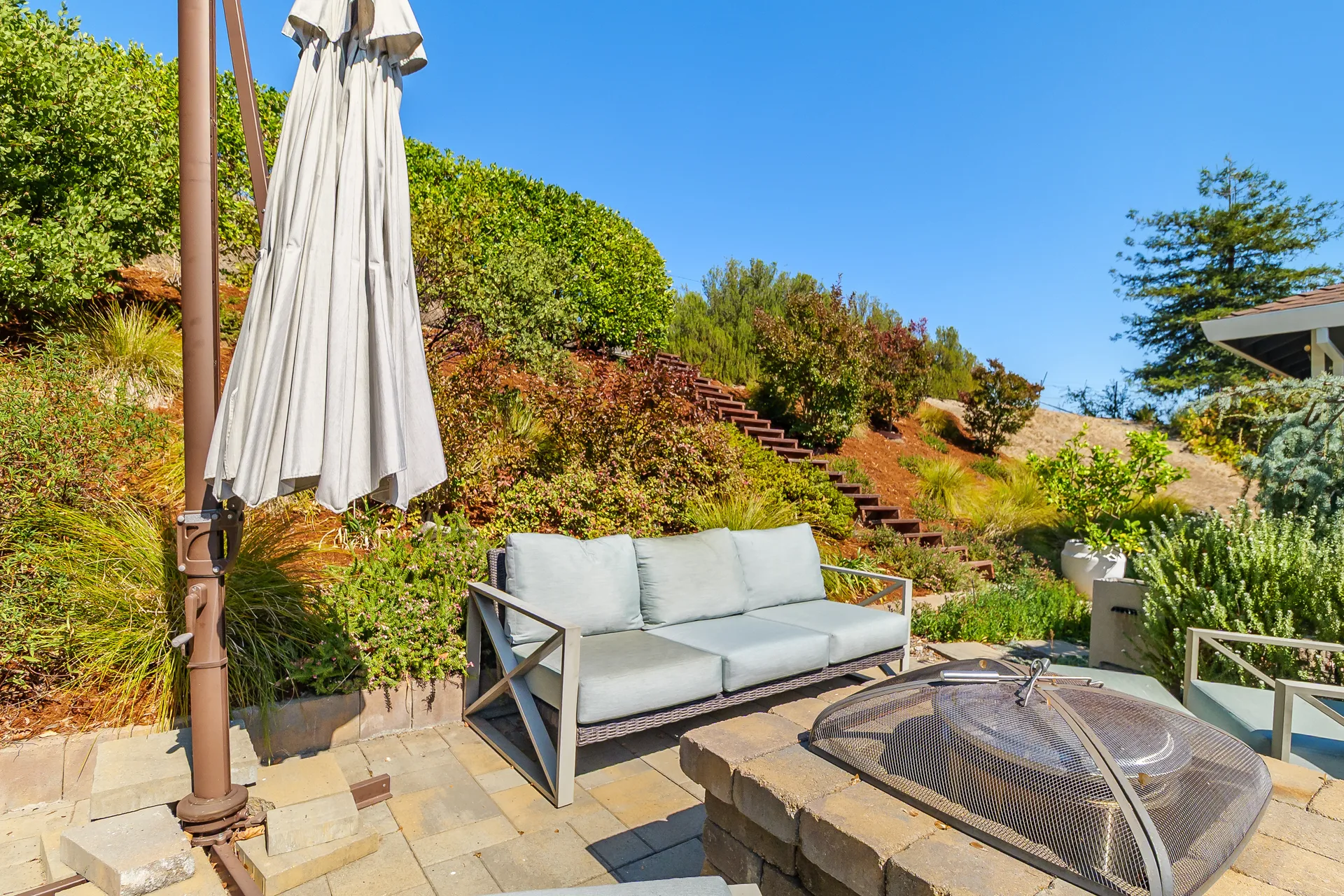 System Pavers patio with built-in stone fire pit and terraced hillside behind