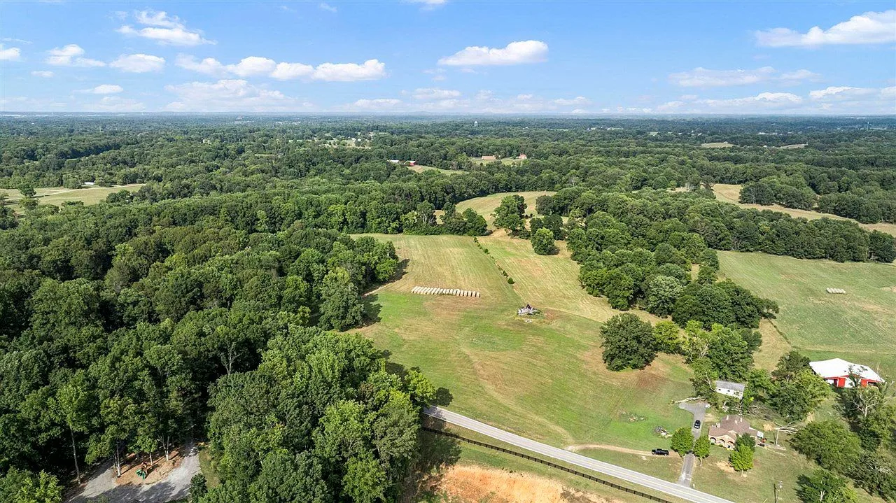 Wide aerial view of the rolling, partially wooded property