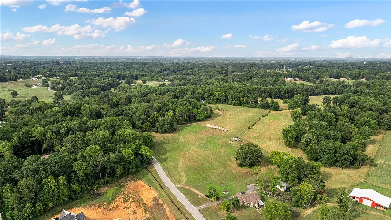 Aerial view across the rolling tract with a rural road below