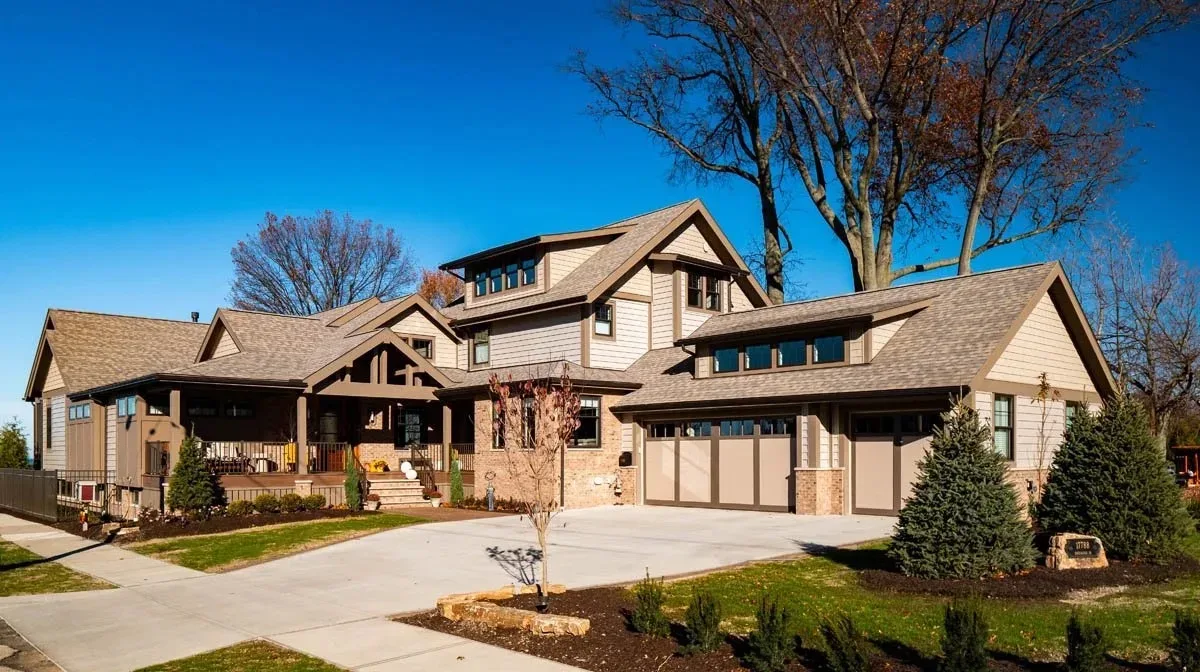 Two-story modern suburban home exterior with wood siding and stone accents in daylight