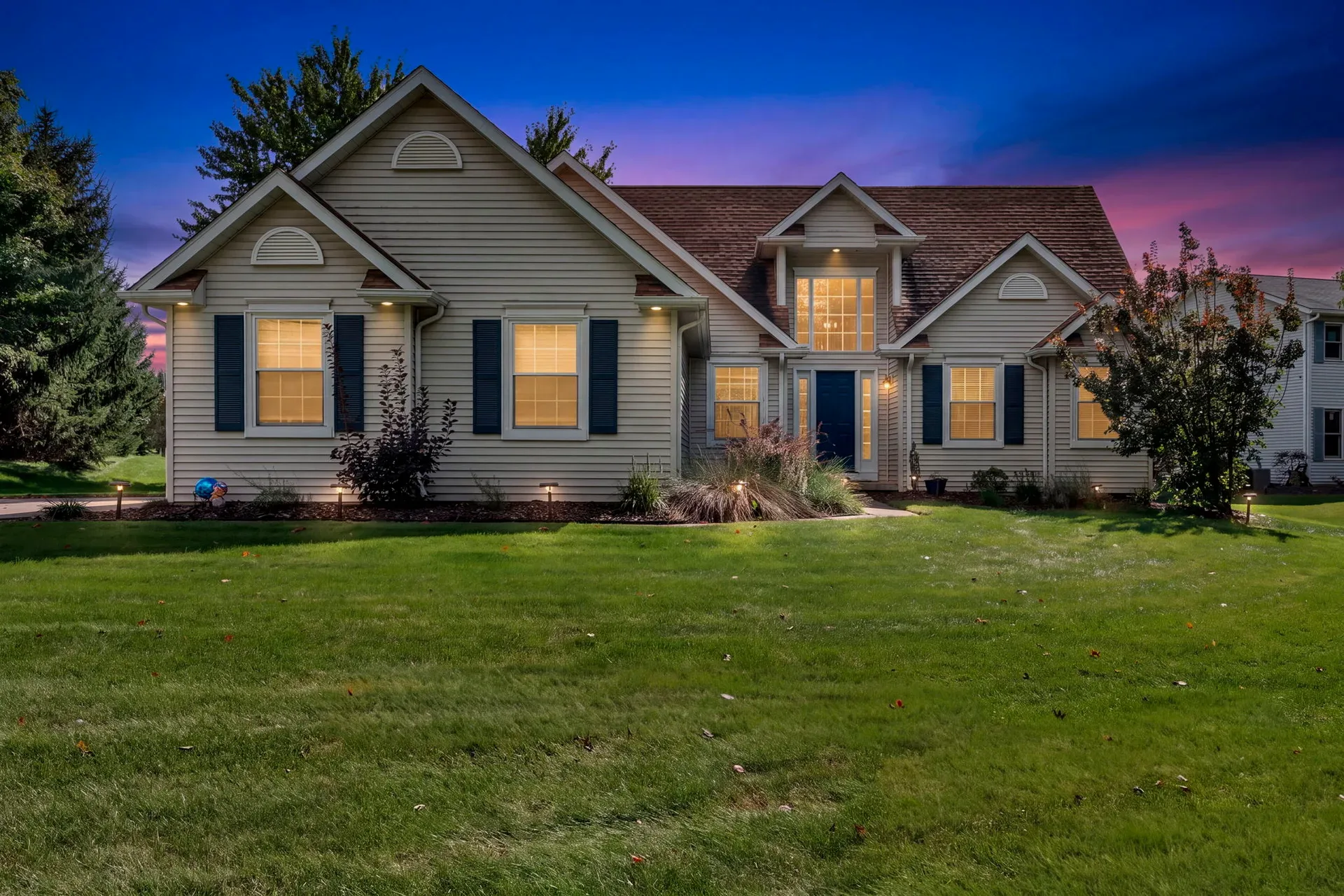Twilight exterior of 188 W Sturbridge Dr, Medina, Ohio, with warm landscape lighting