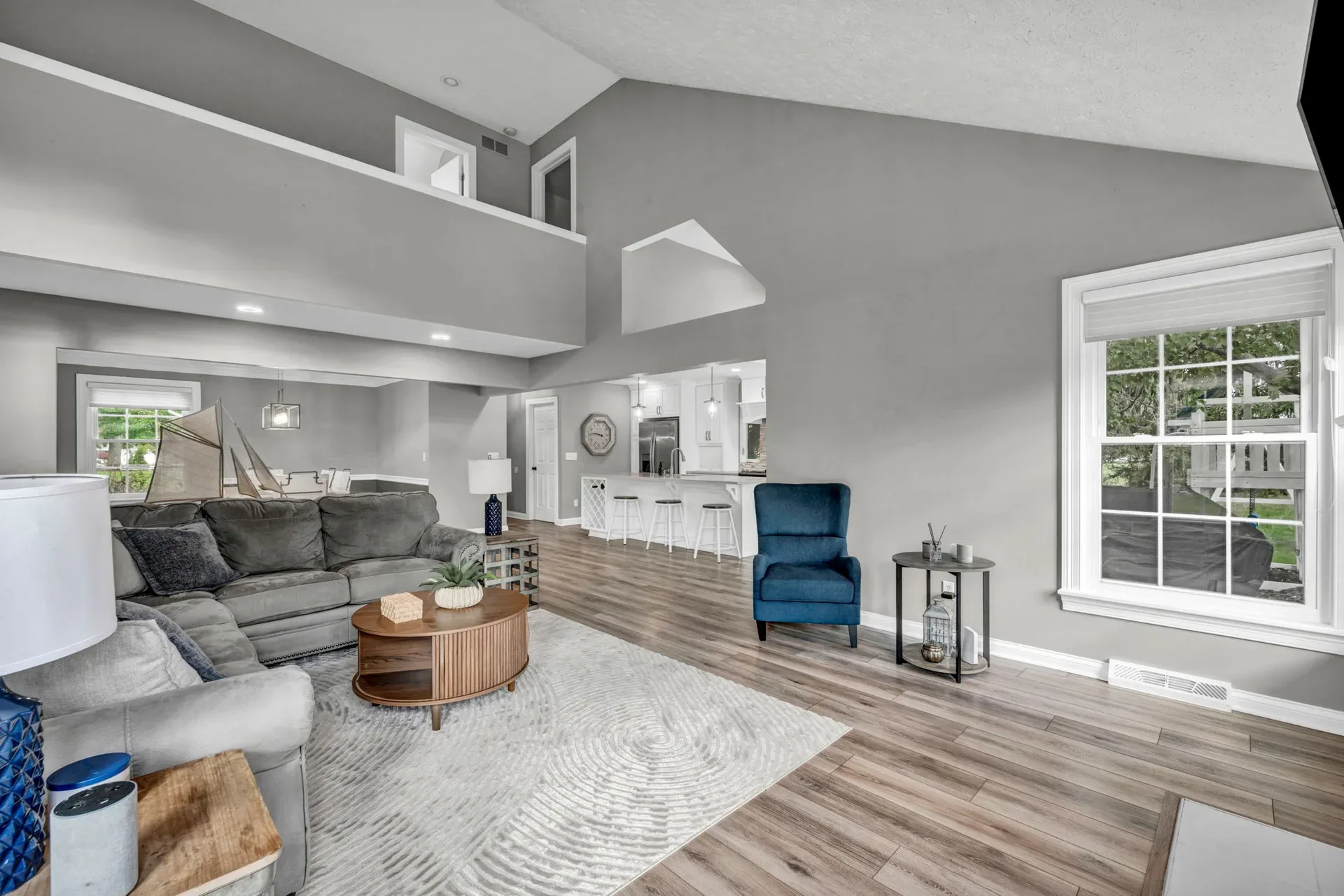 Vaulted-ceiling living room with wood-look flooring and natural light