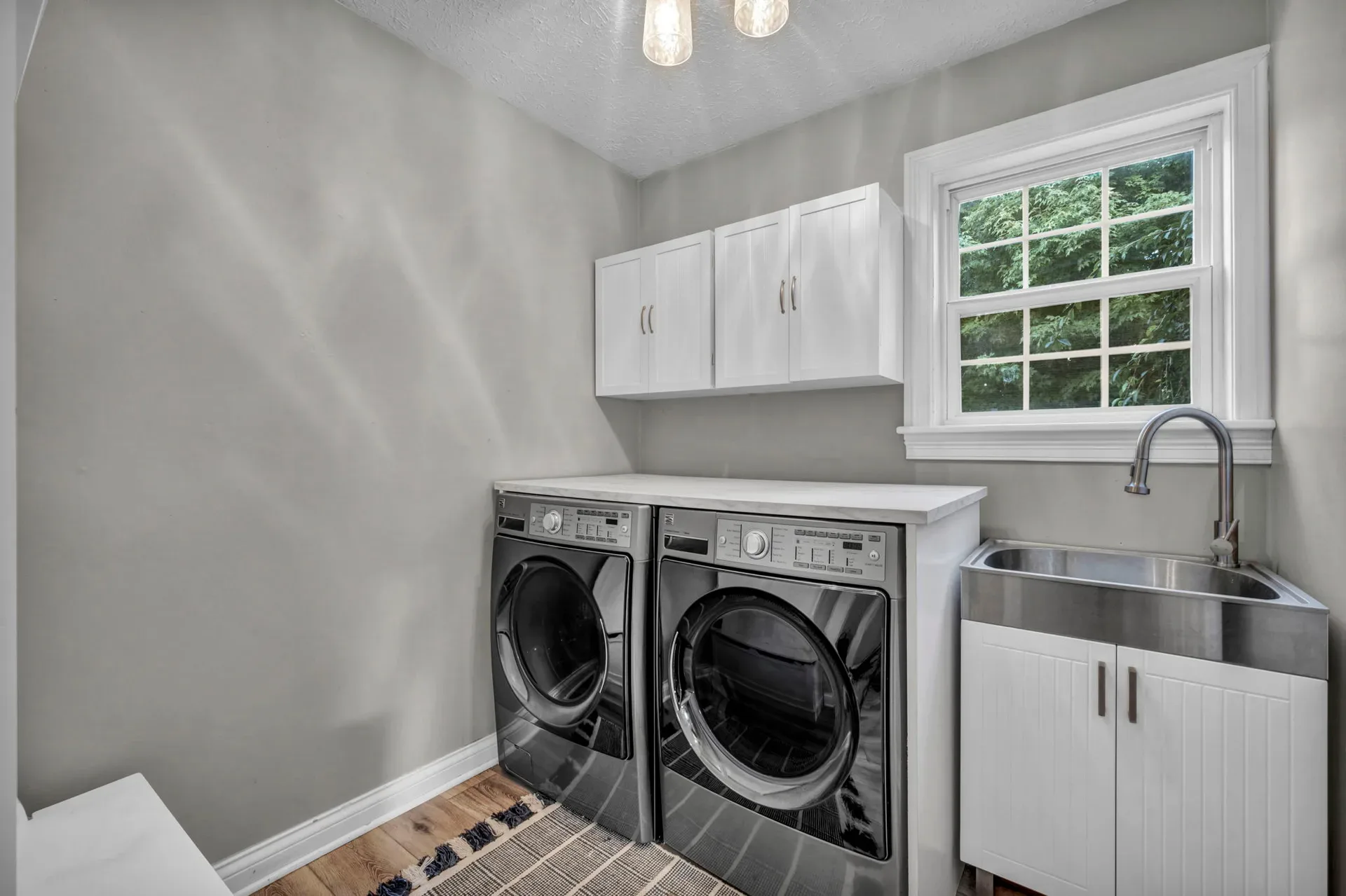 Laundry room with white cabinets and a stainless steel sink