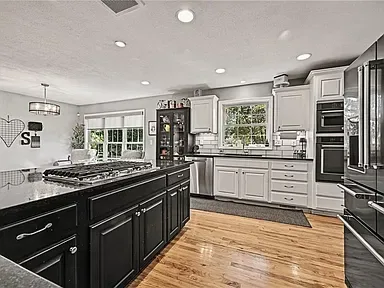 Renovated two-tone kitchen with white wall cabinets, a dark island, and granite countertops at 10035 W 55th Street