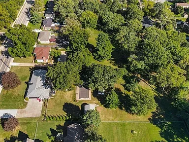 Aerial view of the backyard with the in-ground pool, mature trees, and outbuildings at 10035 W 55th Street