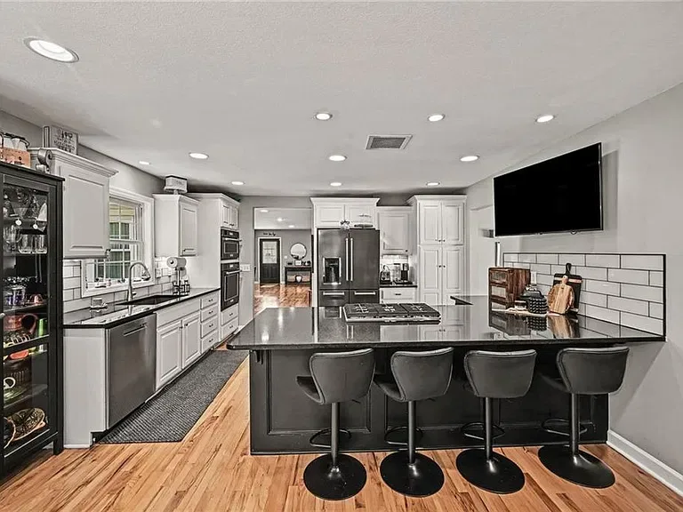 Kitchen with white cabinetry, black granite countertops, and a large island at the Merriam home