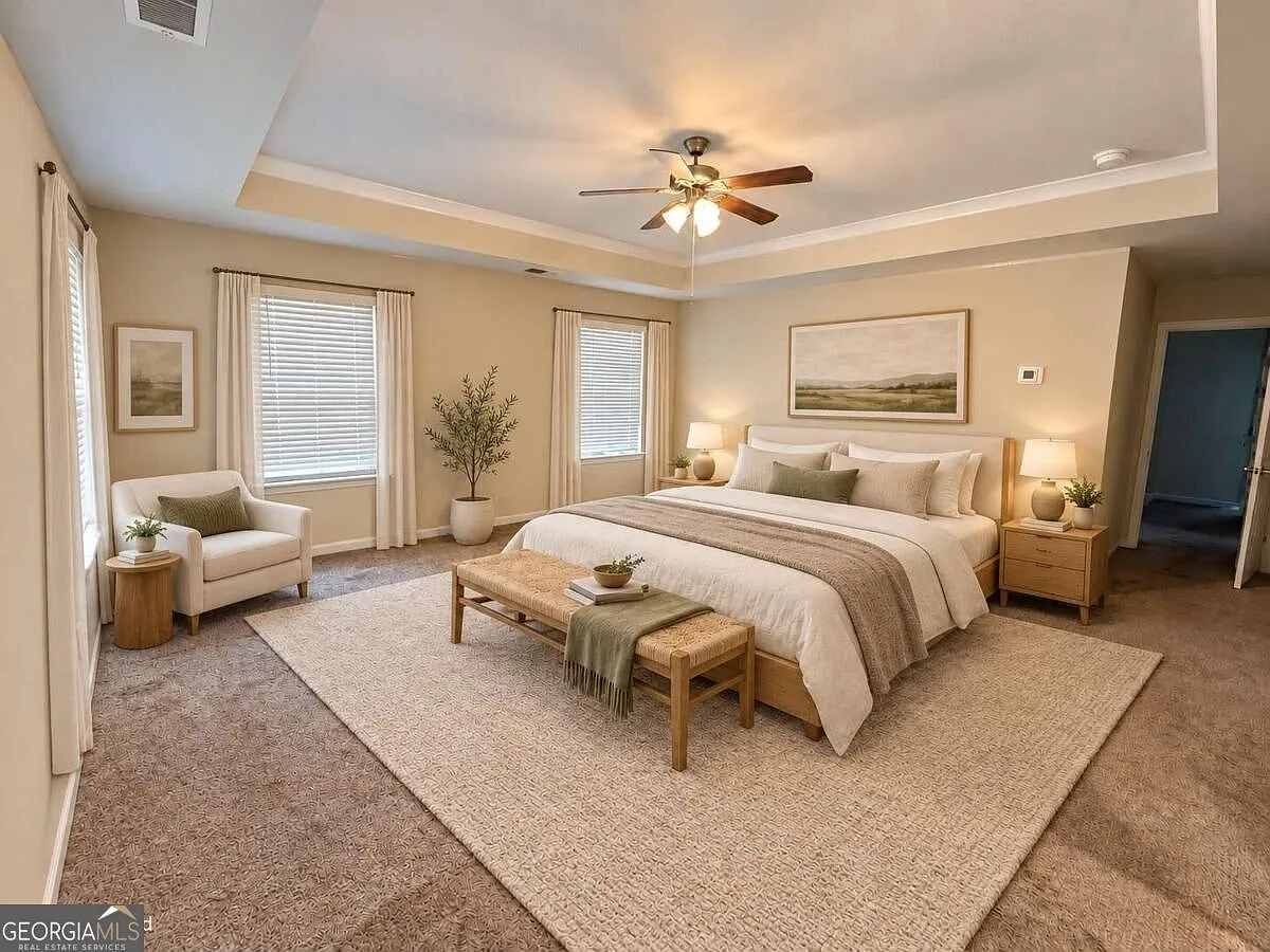 Primary bedroom suite with a tray ceiling and natural light