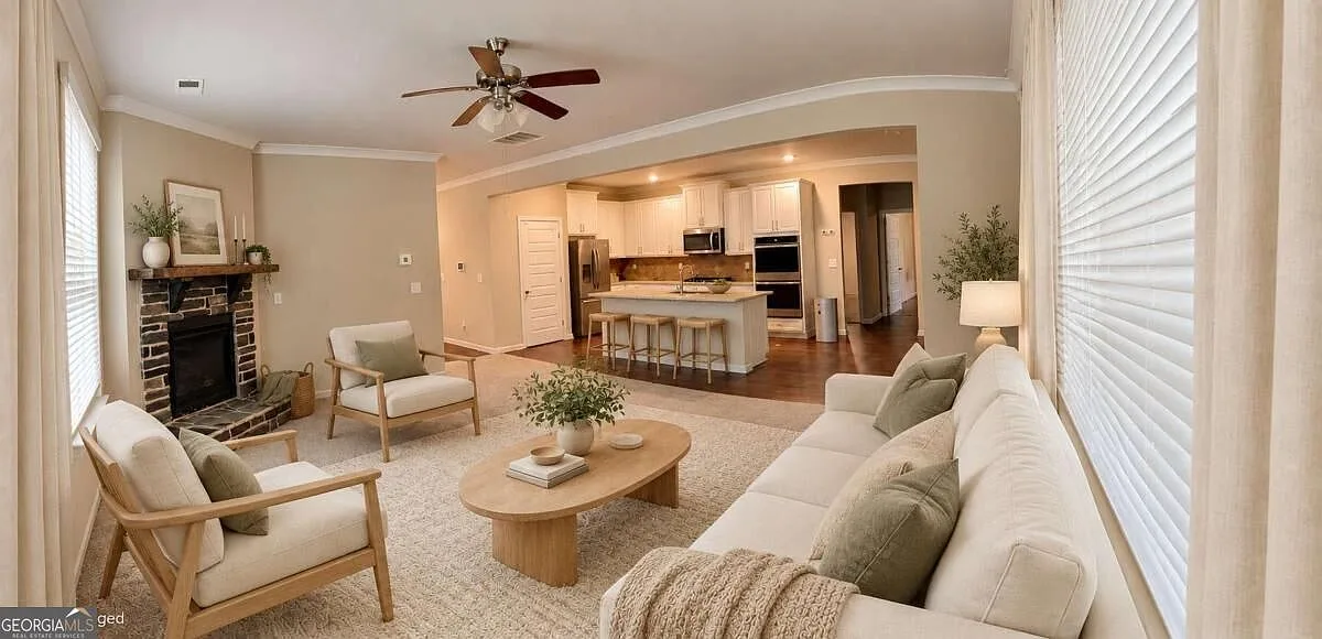 Wide view of the open living room and kitchen with a brick-faced fireplace
