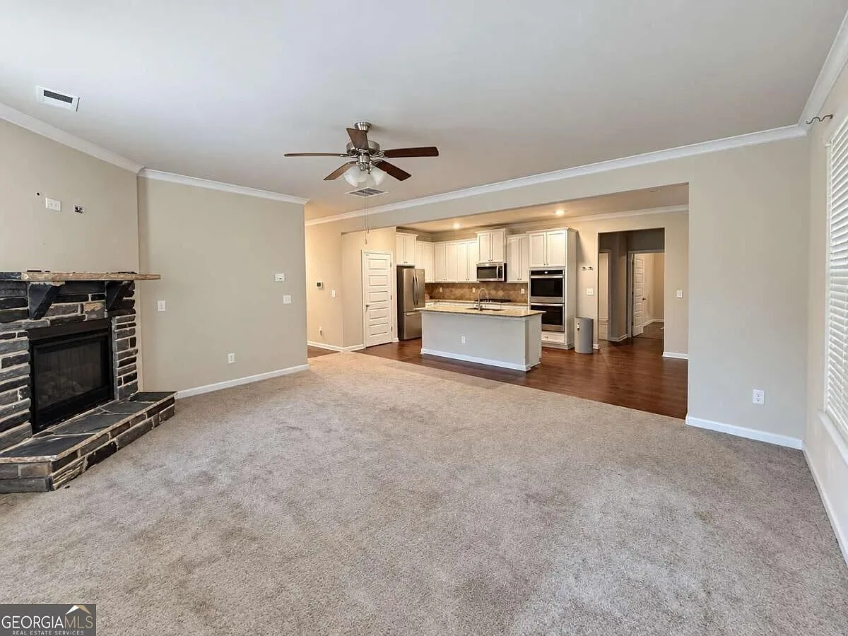 Living room with a stone-faced fireplace adjoining the kitchen