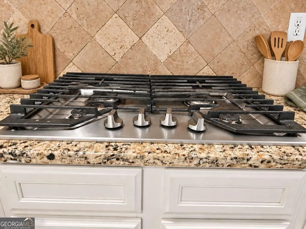 Detail of the gas cooktop, granite countertops and diamond-pattern tile backsplash in the kitchen