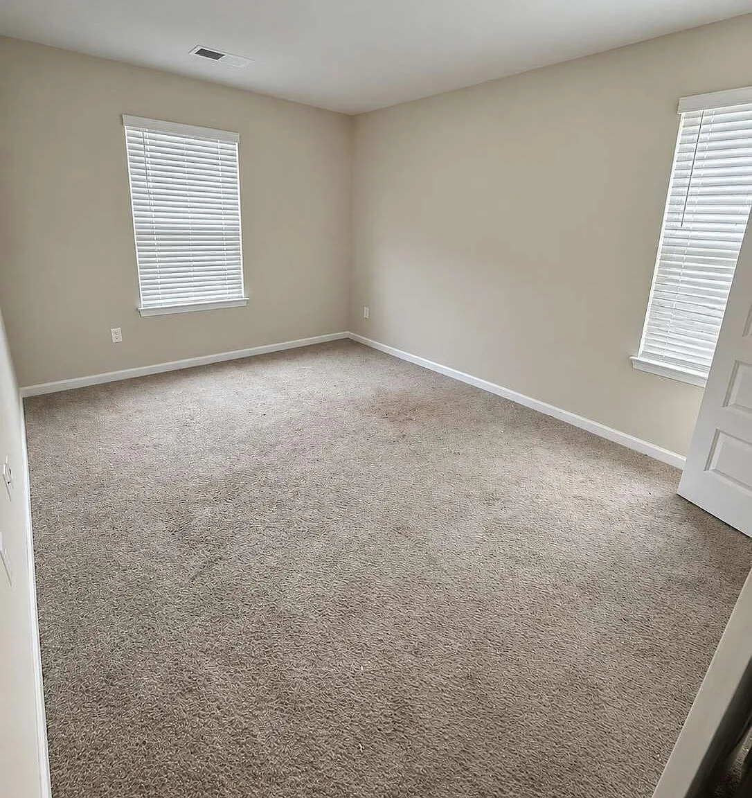 Bright upstairs bedroom with neutral walls and two windows