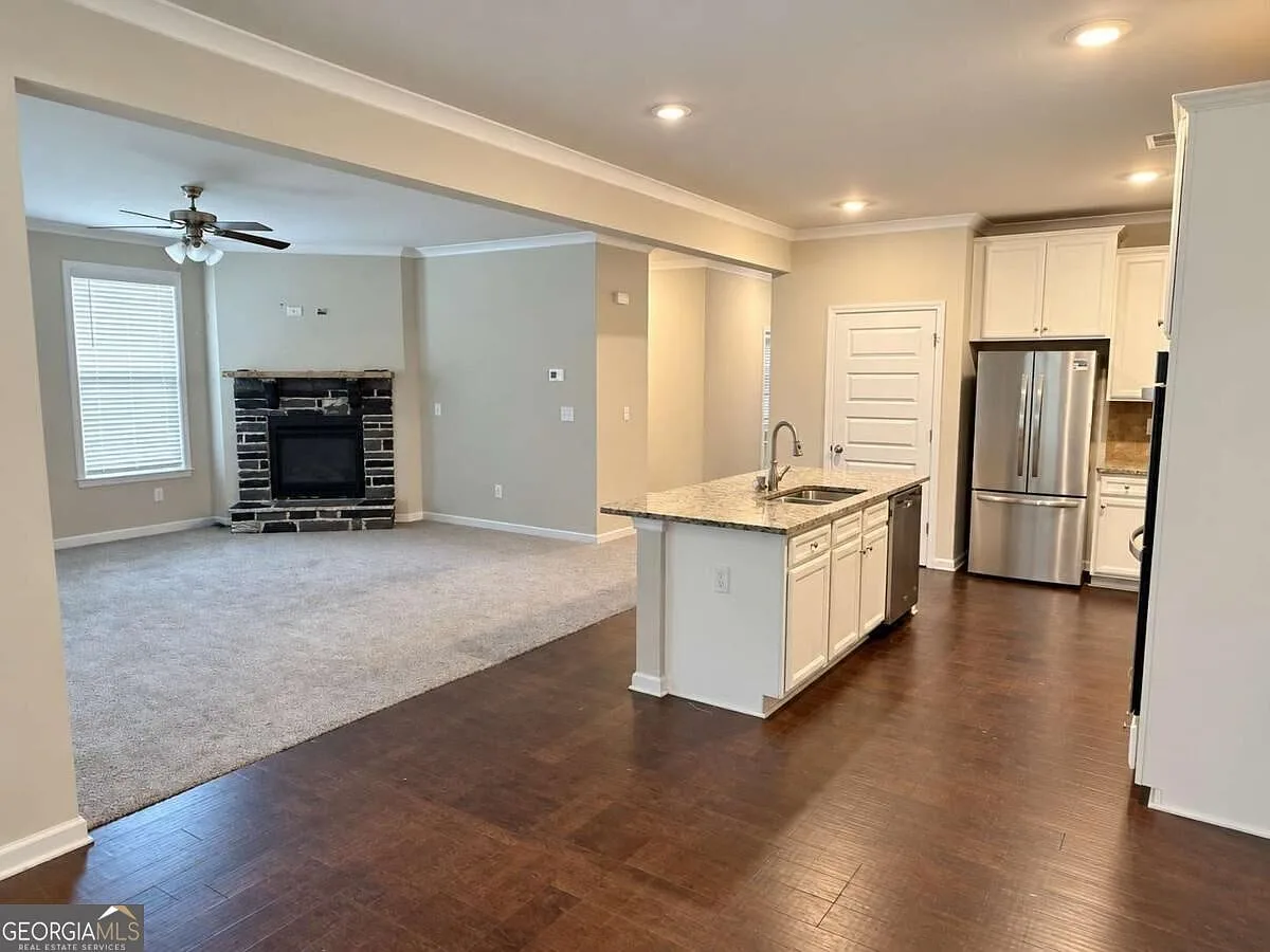 Open-concept kitchen looking toward the living room with stone fireplace