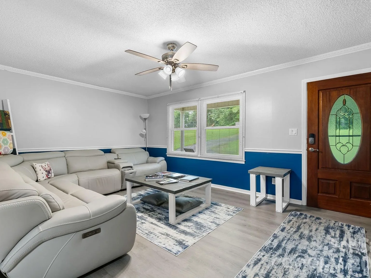 Family room with grey sectional seating and a stained wood front door with decorative glass