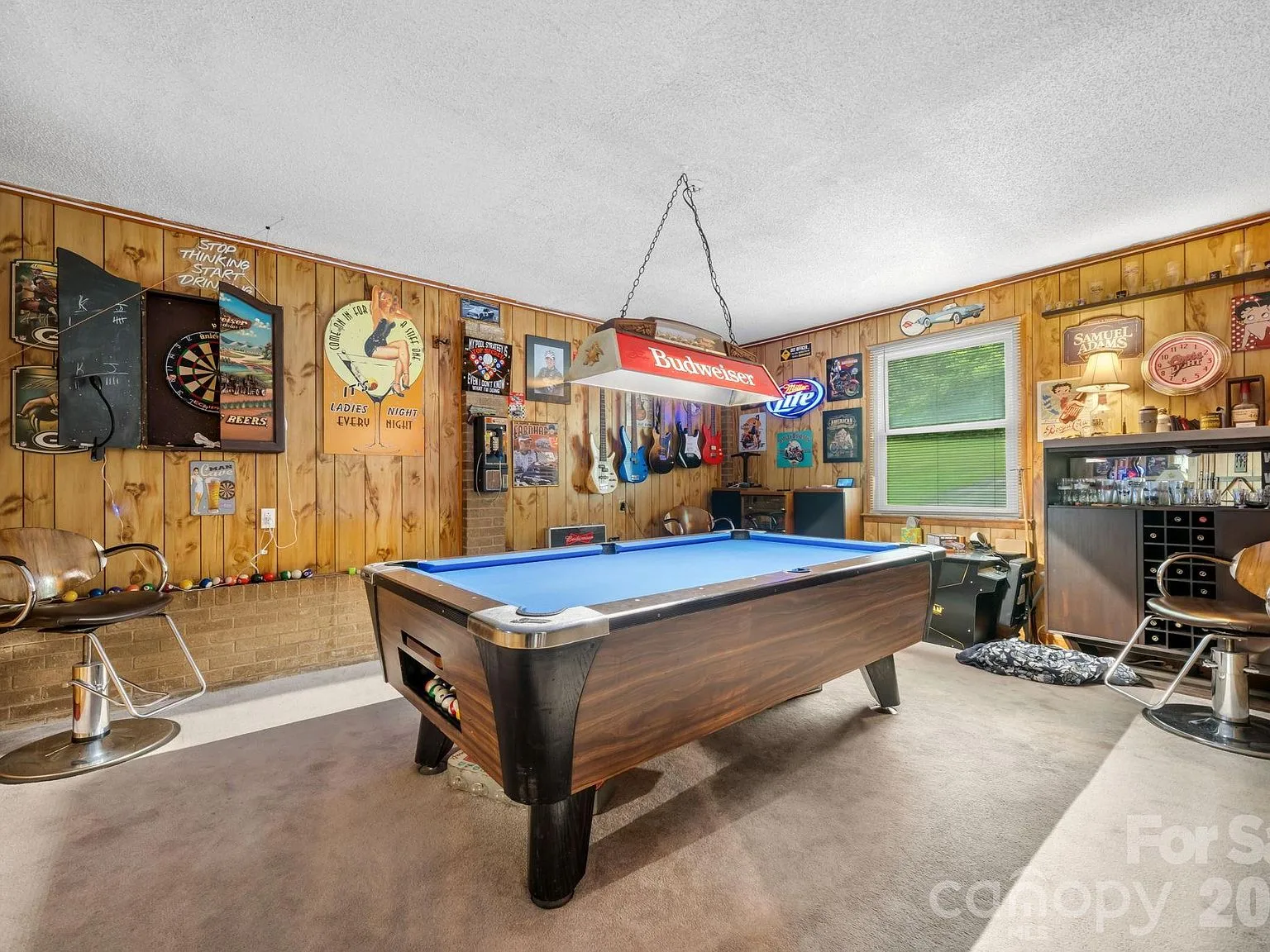 Enclosed garage transformed into a flexible game room with wood-paneled walls and neutral carpet