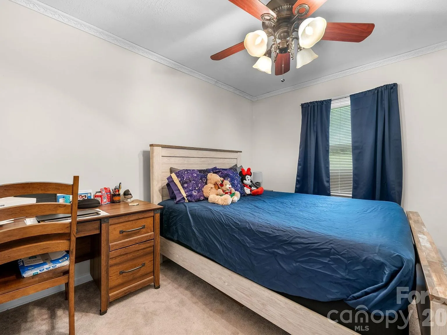 Guest bedroom with beige walls, white crown molding, carpet, and a desk by the window
