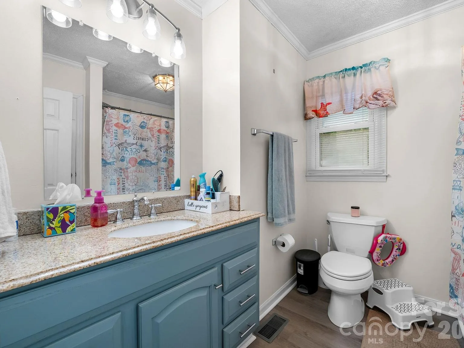 Full guest bathroom with a blue painted vanity, granite countertop, and rectangular mirror