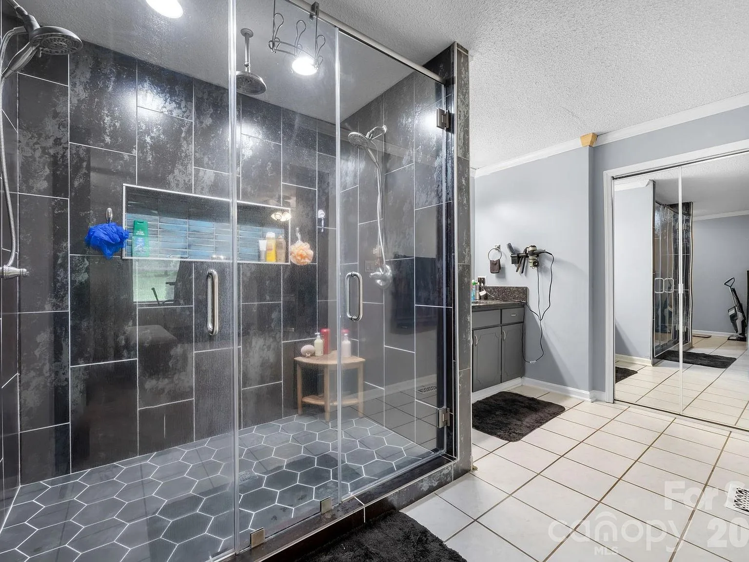 Primary bath walk-in shower with dark grey large-format tile, a hexagonal tile floor, and a glass enclosure