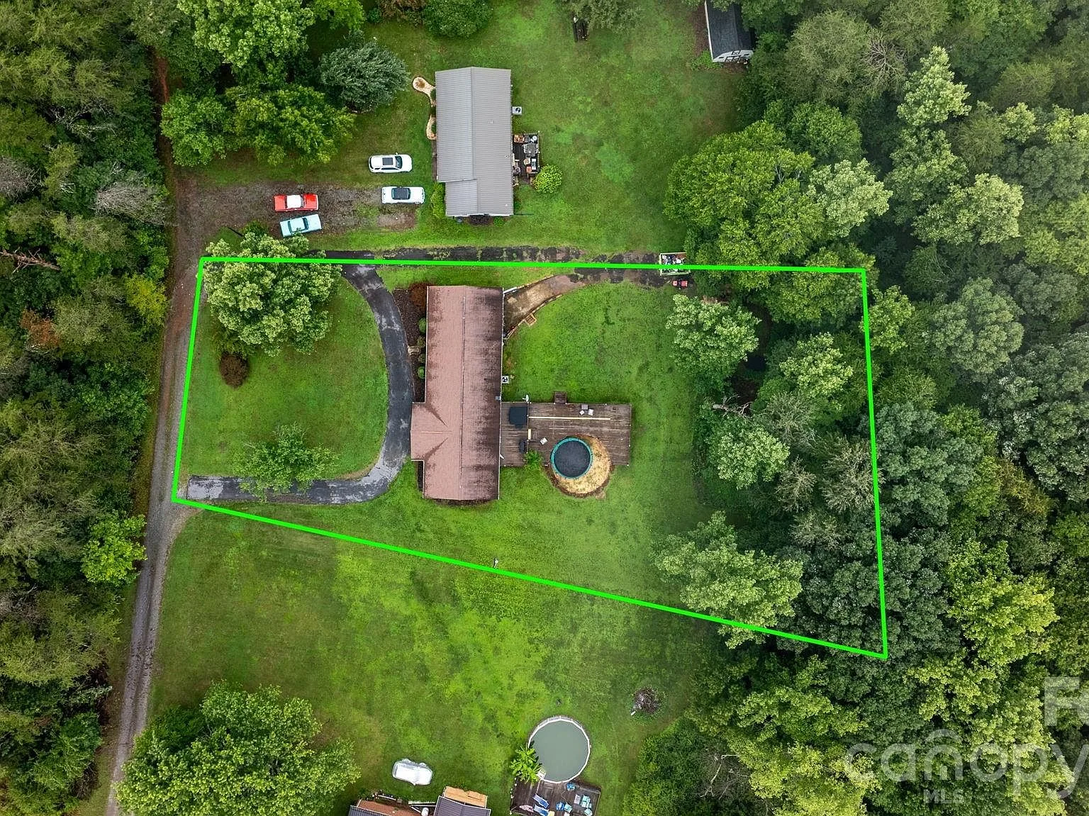 Aerial view of the property at 4690 Worth Pl with mature trees, a long driveway, and a large fenced-free yard
