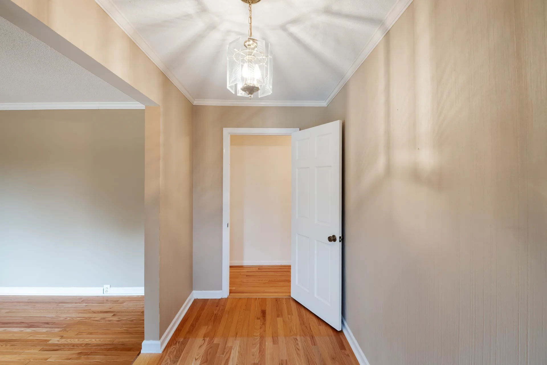 Interior hallway with a chandelier opening into an adjoining room