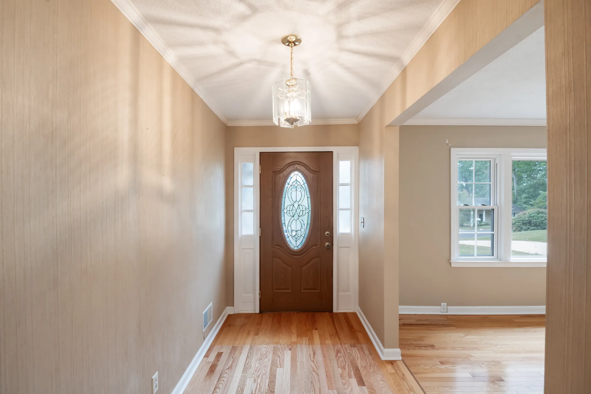Front entryway with a wood front door, oval glass insert, and hardwood floors