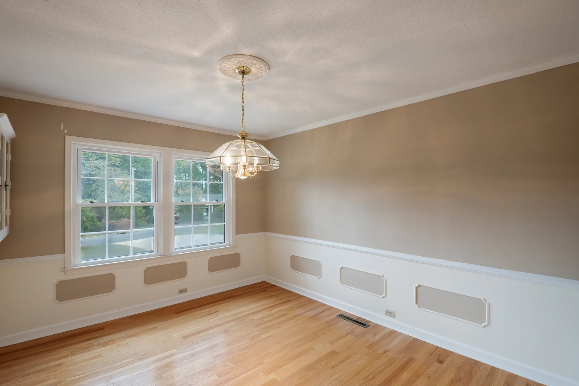 Dining room with two-tone walls, wainscoting, and hardwood flooring