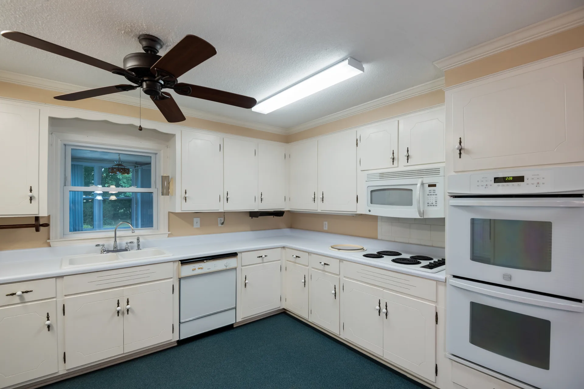Kitchen with white cabinets, white countertops, and appliances