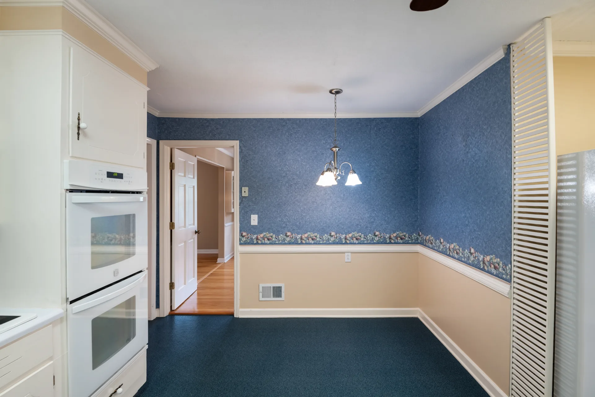 Dining nook off the kitchen with wainscoting and a double oven