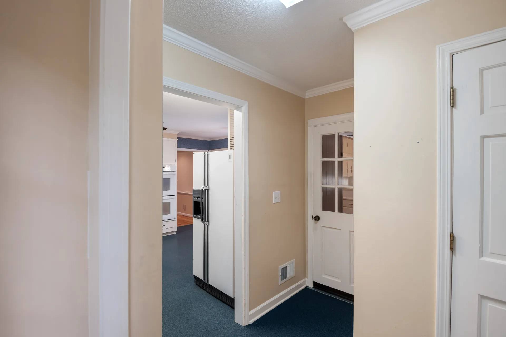 Hallway with crown molding leading toward the kitchen