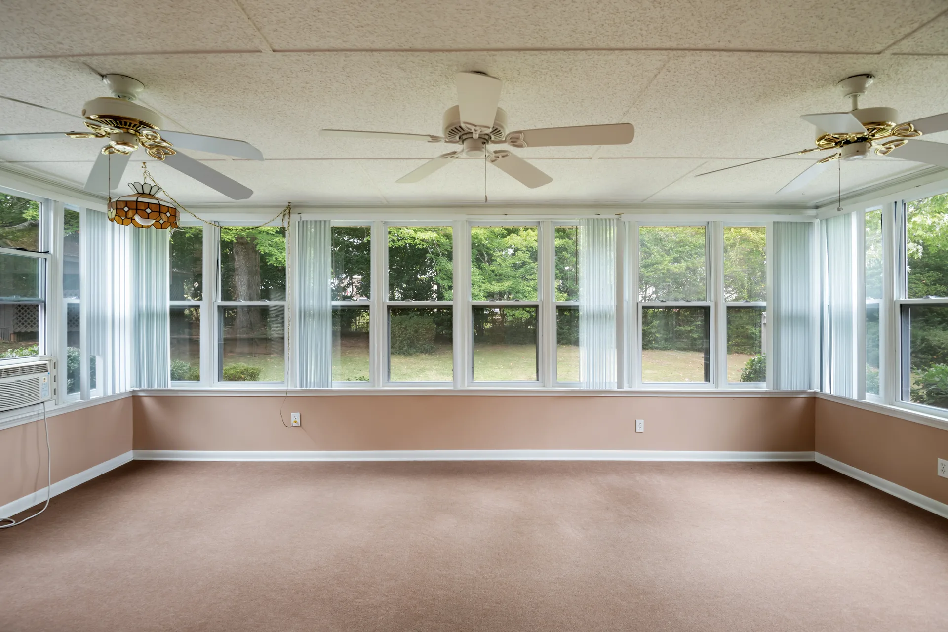 Sunroom with wrap-around windows, vertical blinds, and natural daylight