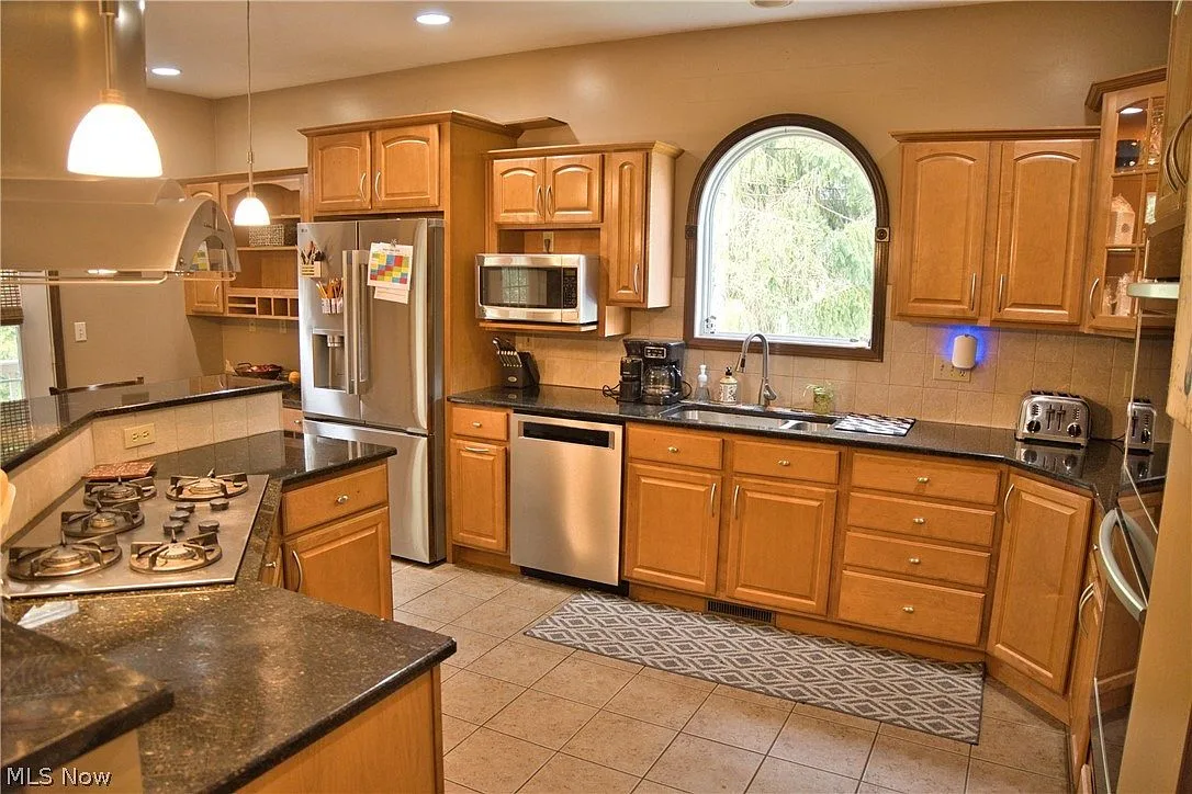 Gourmet kitchen with honey-oak cabinetry, granite counters, and an island cooktop