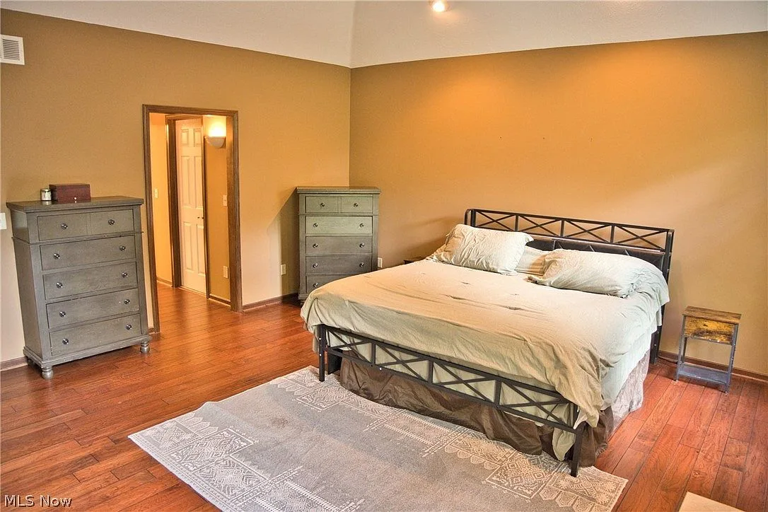 Primary bedroom suite with vaulted ceiling and hardwood floors