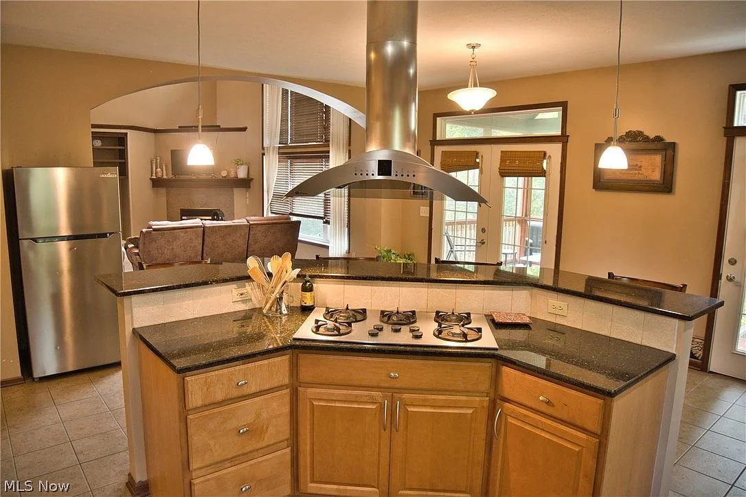 Kitchen island cooktop with a stainless steel chimney range hood