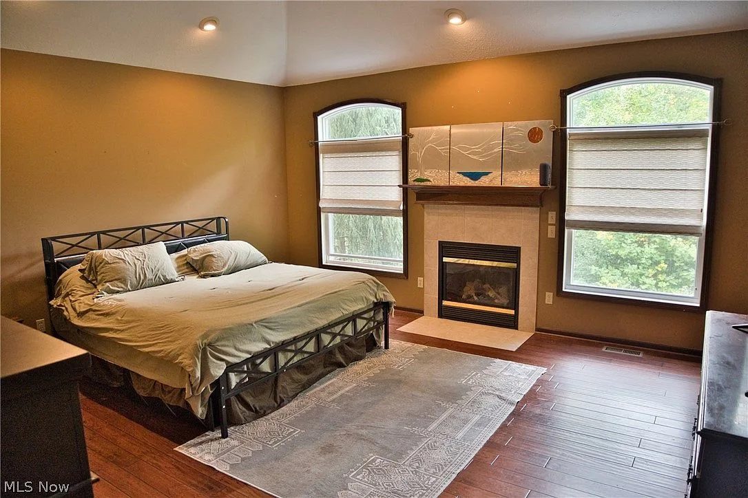 Primary bedroom with vaulted ceiling, fireplace, and arched windows