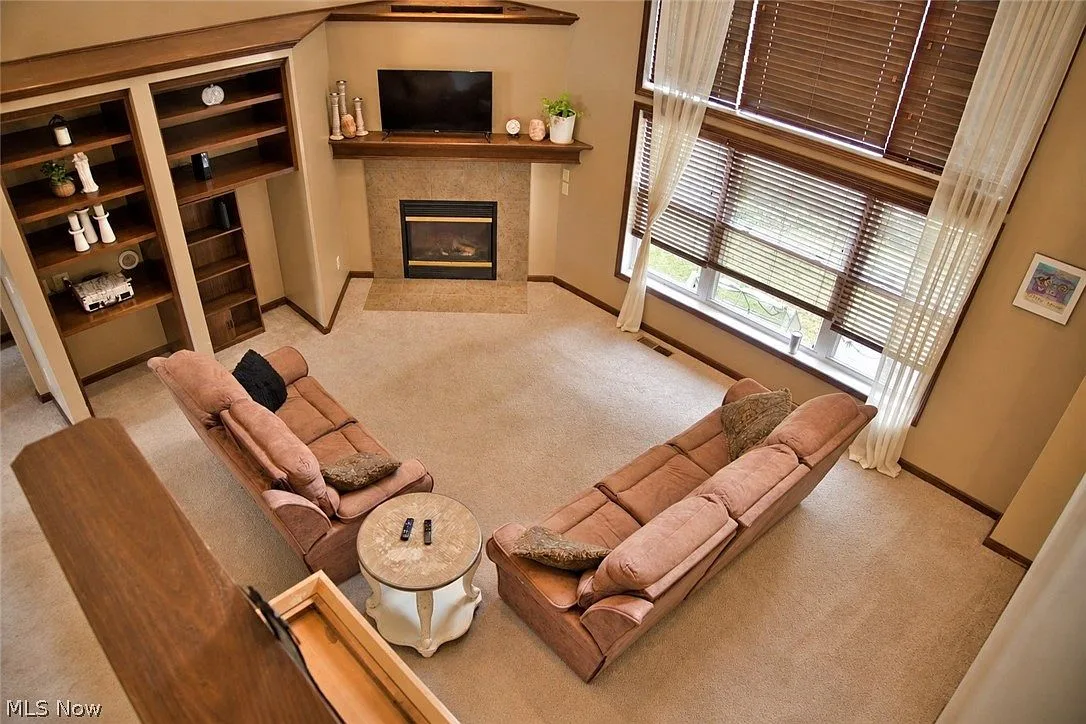 Two-story living room viewed from the upper landing, with fireplace and built-in shelving