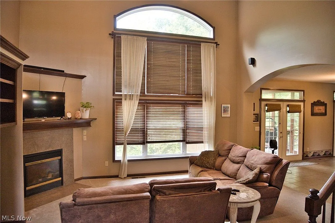 Two-story living room with stacked-stone fireplace and arched windows