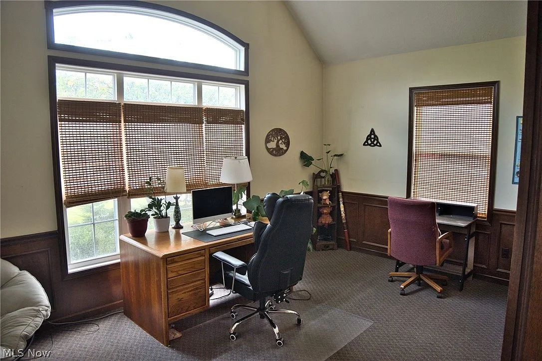 Home office with wainscoting, vaulted ceiling, and a large window