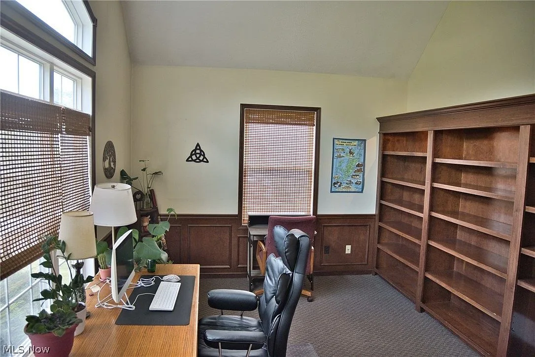 Home office with tall built-in wooden bookshelves and natural light