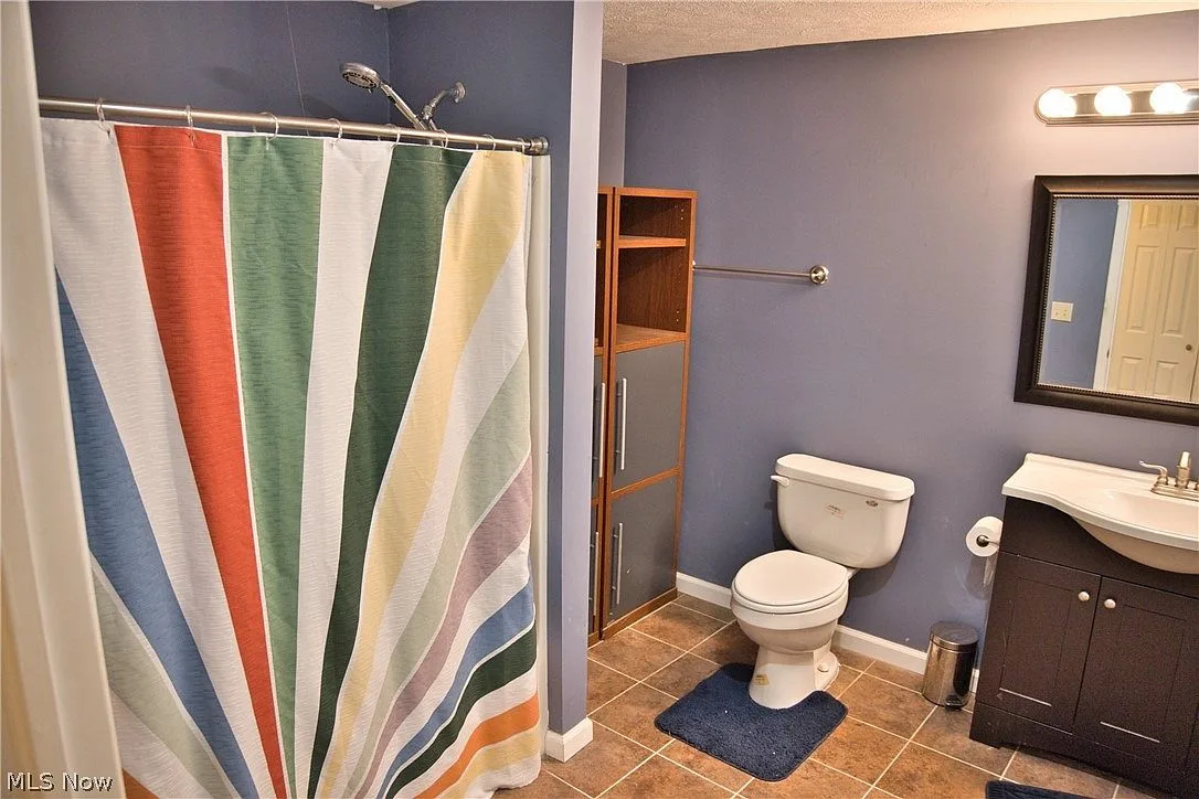 Secondary bathroom with blue walls and tile flooring